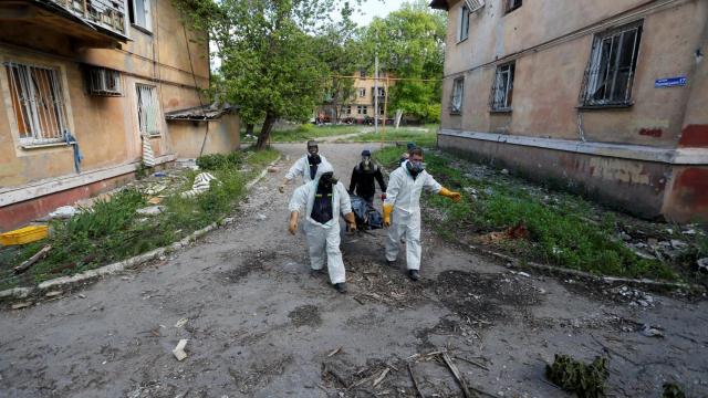 Especialistas transportan el cuerpo de una persona muerta durante el conflicto.