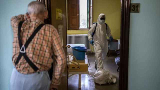 Un anciano espera en el marco de su habitación mientras la desinfectan, en una residencia.