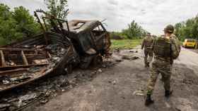 Soldados ucranianos patrullando este sábado 28 de mayo, en medio de vehículos destruidos durante una batalla en la entrada de la ciudad de Járkov (Ucrania).