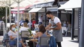 Un camarero sirve a unos clientes en un bar de Málaga.