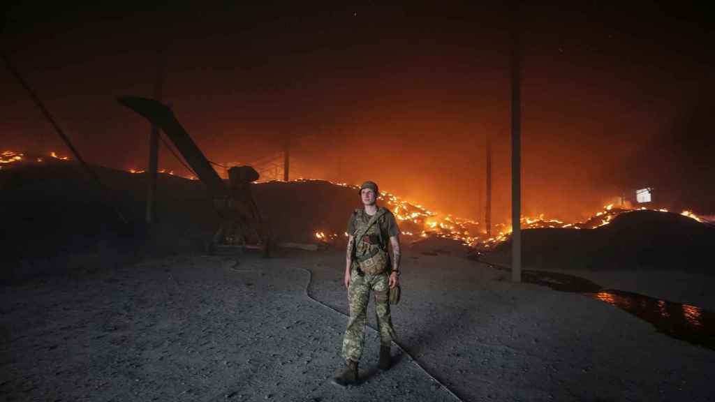 Un militar ucraniano camina mientras las semillas se queman en un silo de grano después de que fuese bombardeado repetidamente, en medio de la invasión rusa de Ucrania, en la región de Donetsk