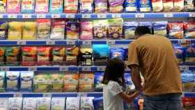 Un padre mira los precios de los alimentos en un lineal de un supermercado.