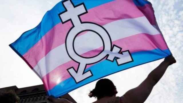 Una persona sujeta una bandera trans.