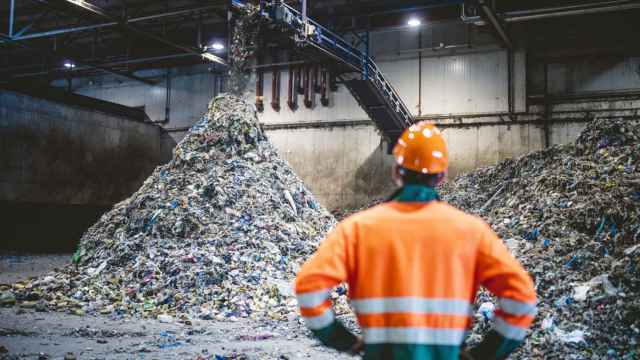 Un trabajador de una planta de reciclaje observando el proceso de gestión de residuos.