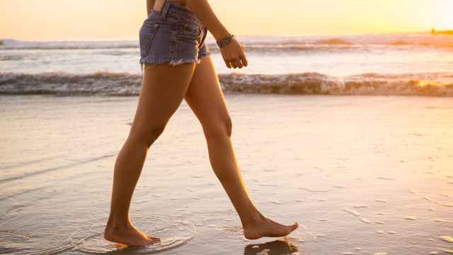 Las piernas de una mujer caminando por la playa.