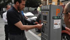 Óscar Puente saca un billete de bus ordinario en un parquímetro de Valladolid.