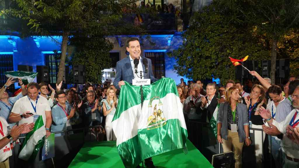 Juanma Moreno, con una bandera de Andalucía, anoche a las puertas de la sede del PP en Sevilla.