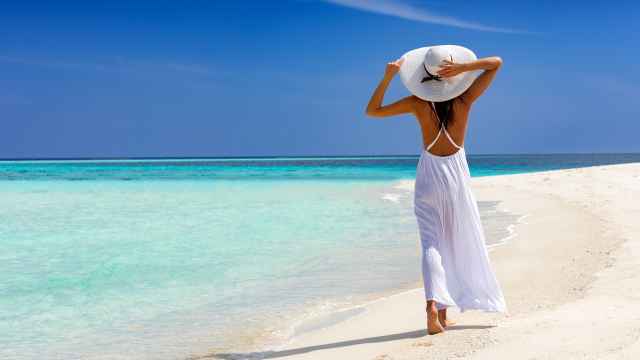 Una mujer felizmente caminando por una playa tropical.