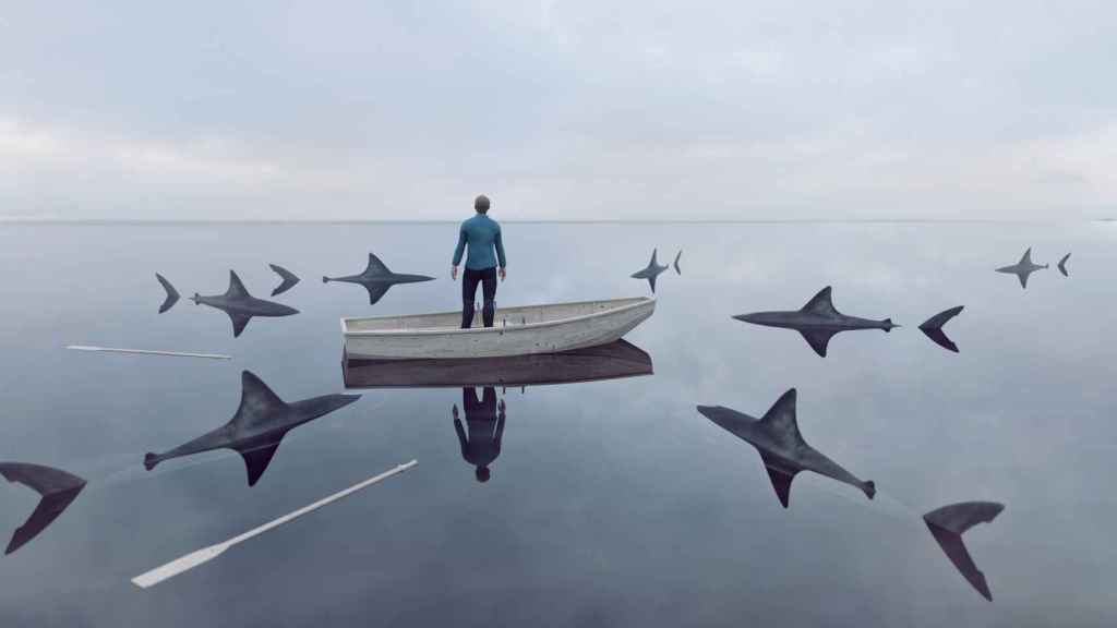 Imagen de archivo de un hombre perdido en el mar rodeado de tiburones.