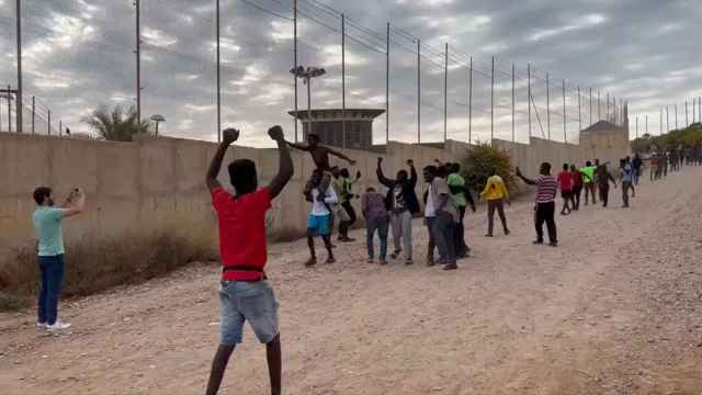 Migrantes celebran haber logrado cruzar a Melilla tras superar la valla este viernes.