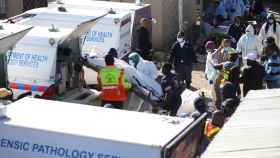 Personal forense evacúa los cadáveres del bar Enyobeni Tavern, en la ciudad sudafricana de East London.