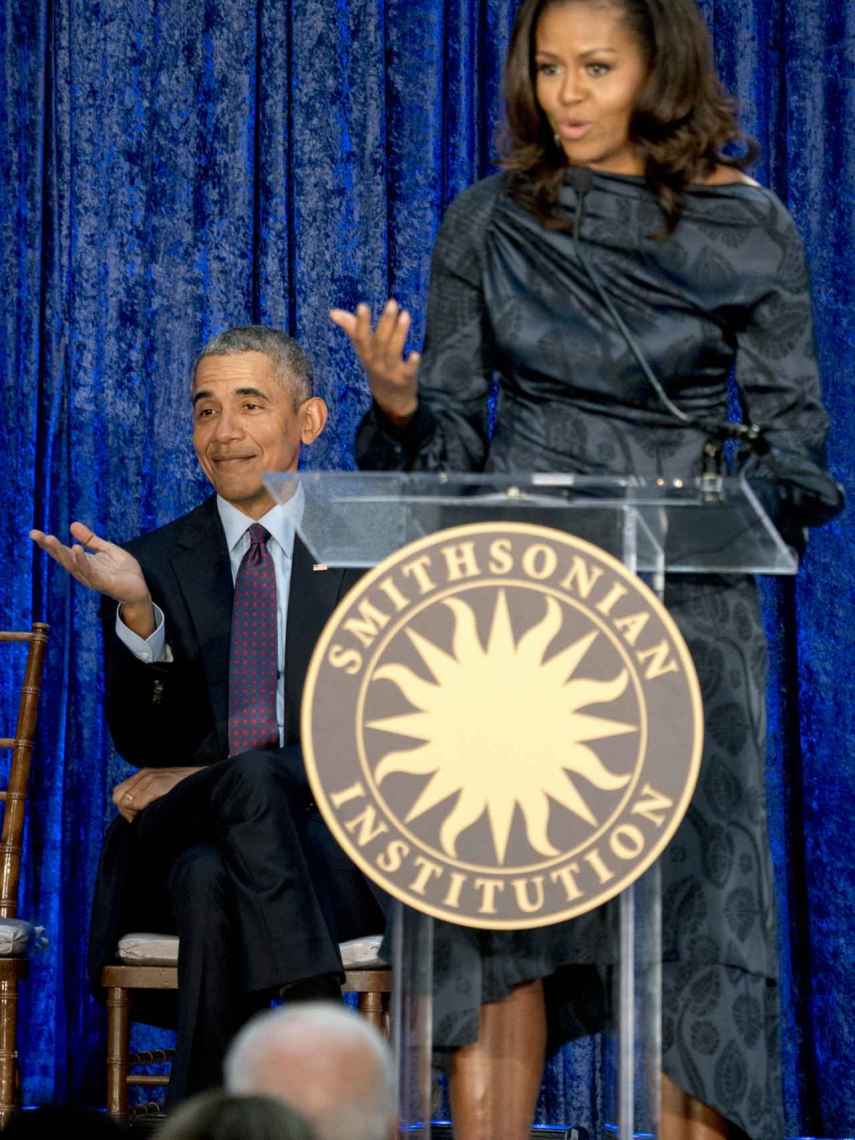 barack Obama escucha a su esposa mientras esta habla de sus retratos.