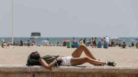 Una persona tumbada en la entrada de una playa valenciana, en imagen de archivo.