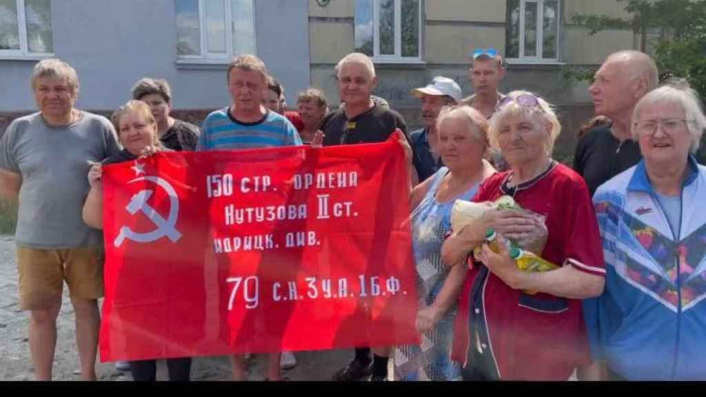 Ciudadanos de Lisichansk reciben a las tropas rusas con una bandera sociética.