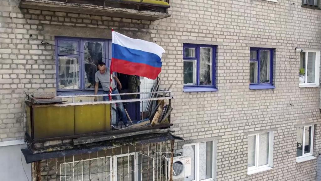 A Russian flag flies from a balcony in Lisichansk