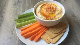 Un cuenco de hummus con palitos de verduras.