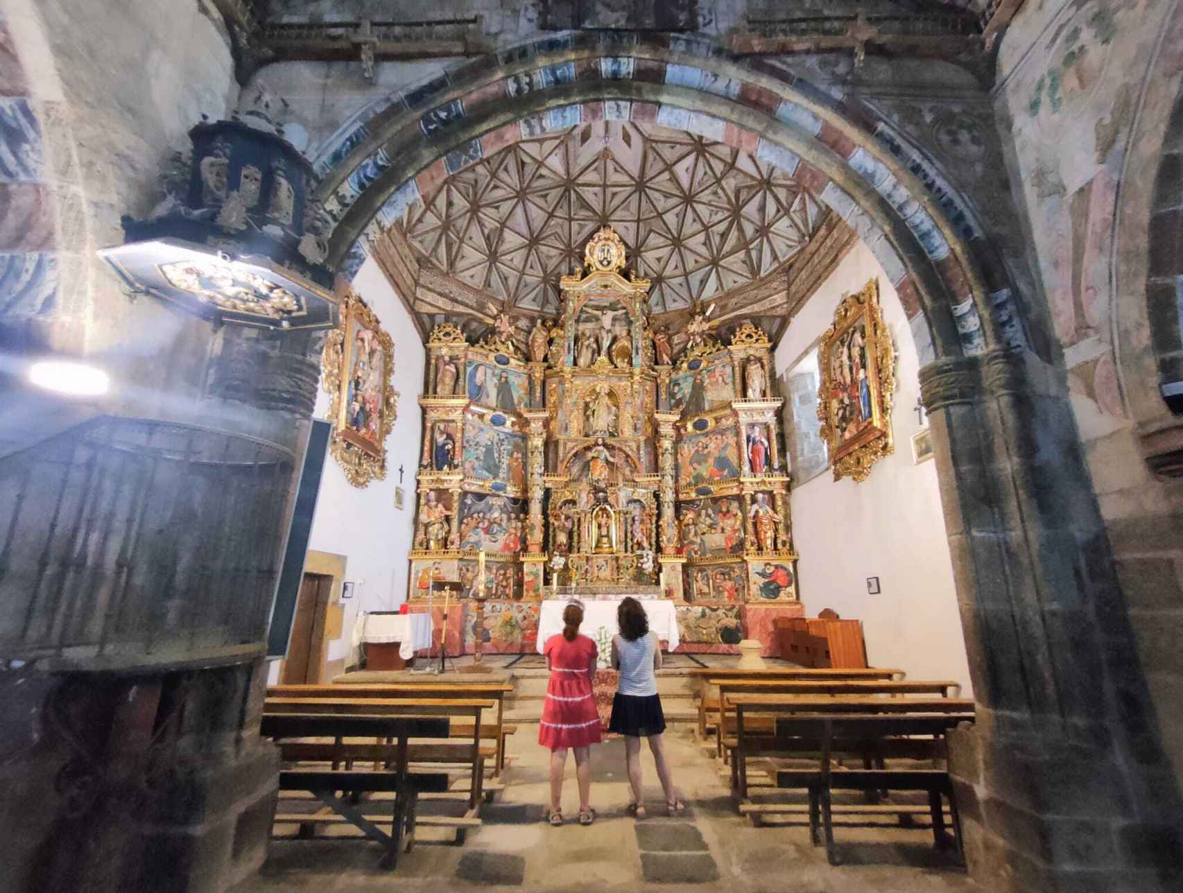 Dos turistas frente al altar renacentista de la iglesia de Santo Tomas Apostol.
