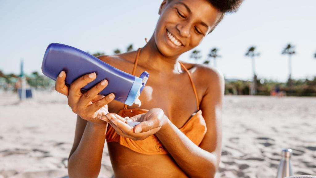 Mujer aplicándose protector solar en la playa