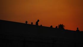 Varias personas pasean por el puente romano de Córdoba al atardecer en una jornada donde continua la ola de calor con temperaturas que alcanzan los 43 grados.