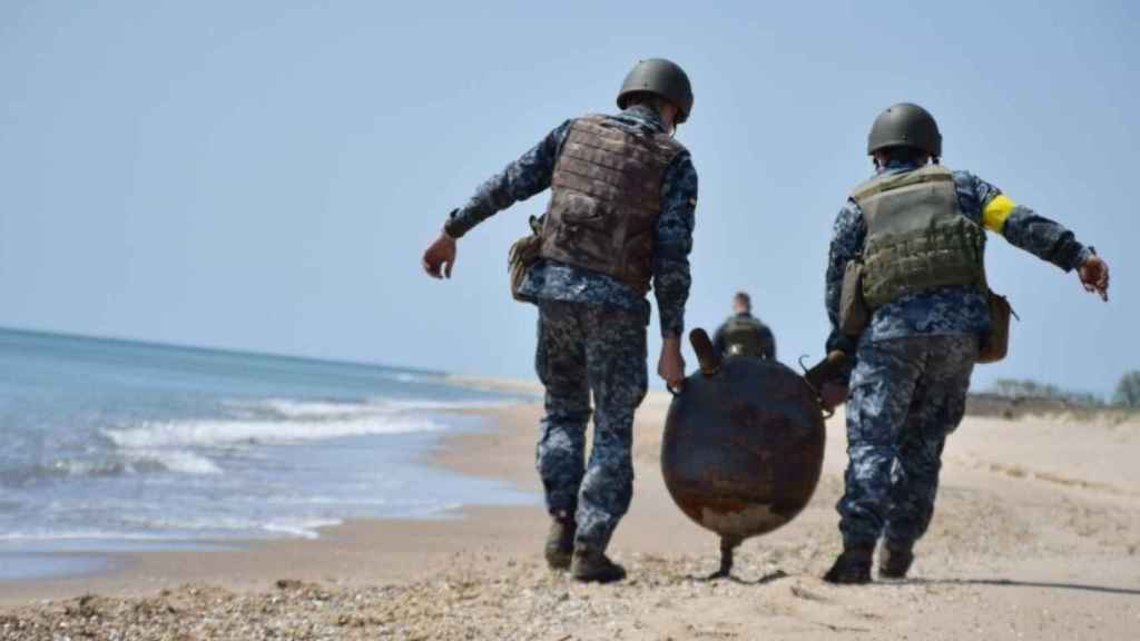 Dos soldados ucranianos desactivan una mina rusa en la playa de Odesa.