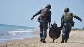 Dos soldados ucranianos desactivan una mina rusa en la playa de Odesa.