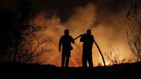 Dos bomberos trabajan en las labores de extinción de un fuego.