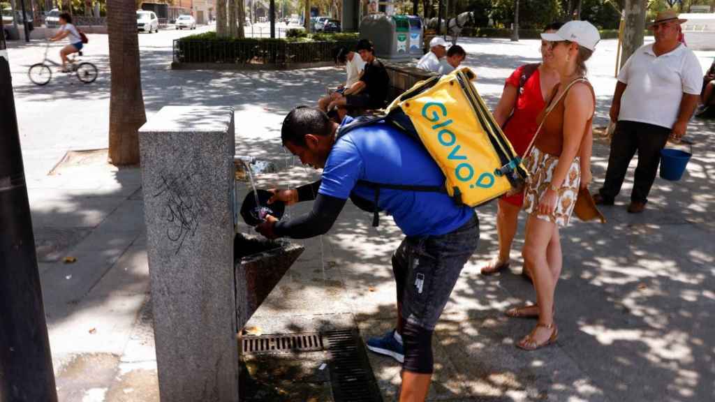 Un trabajador de Glovo se refresca en una fuente en Sevilla el pasado 11 de julio.