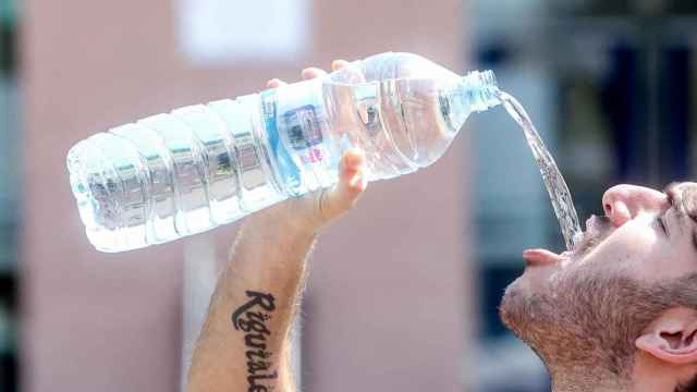 Un joven bebe agua de una botella.
