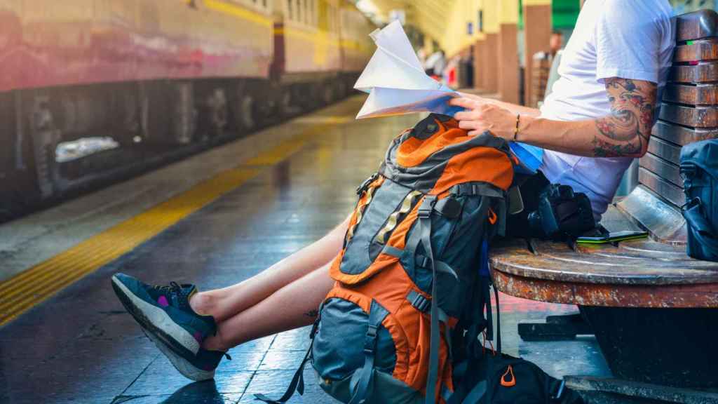 Foto de archivo de un mochilero que consulta un mapa mientras espera al tren.