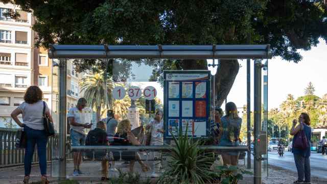 Un grupo de personas espera al autobús en una parada de la EMT en la Alameda de Málaga.