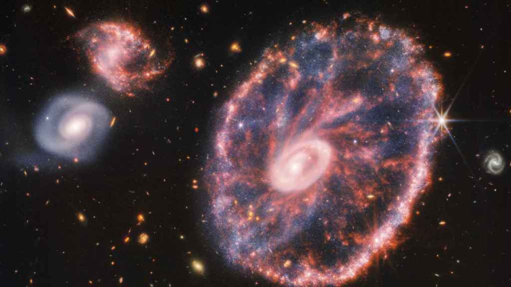 La potente mirada infrarroja del telescopio James Webb ha logrado una instantánea detallada de Rueda de Carro, pero también de dos galaxias compañeras más pequeñas con un telón de fondo de muchas otras galaxias
