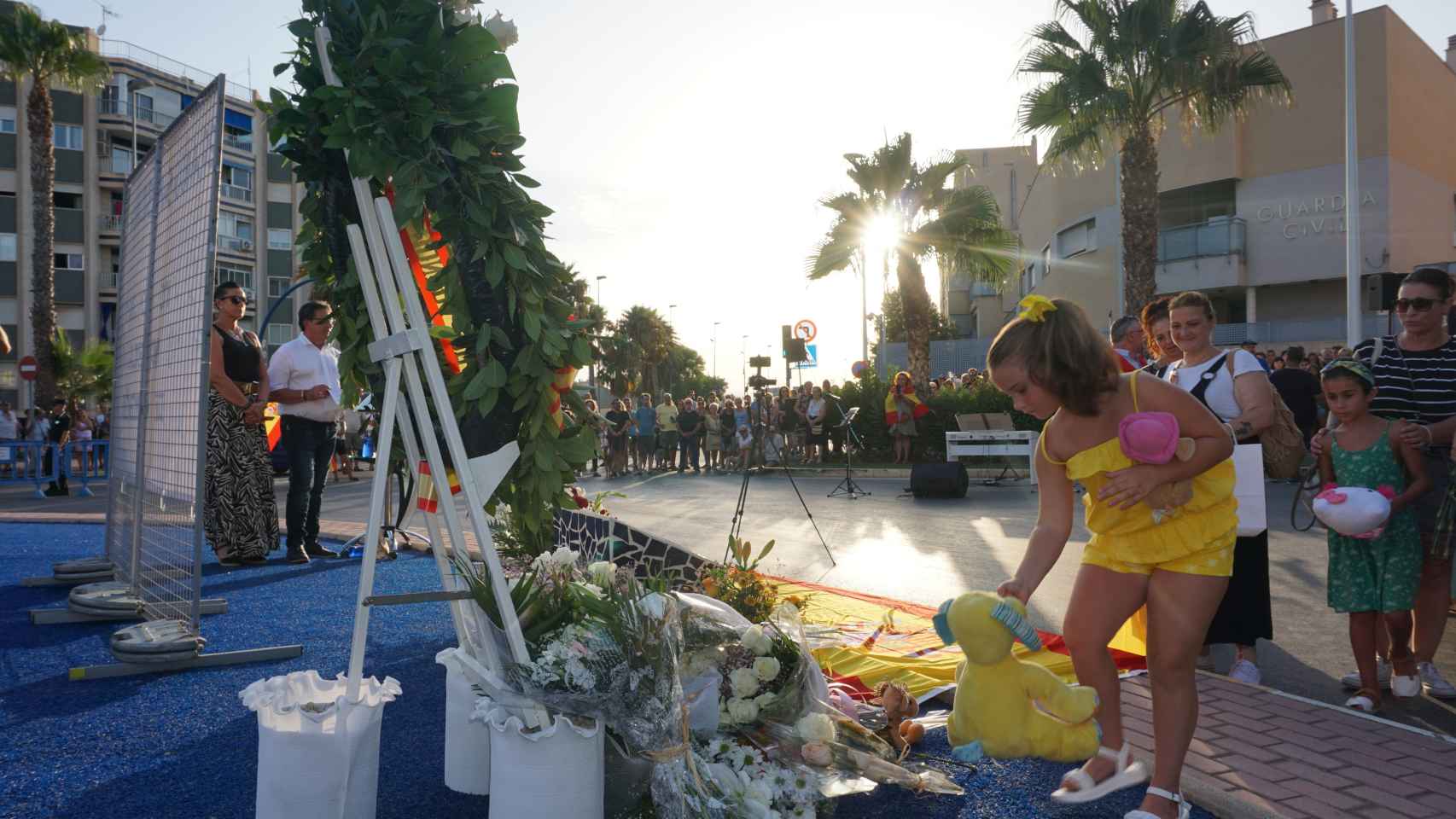 Una niña deja un peluche en la placa en recuerdo de Silvia Martínez.
