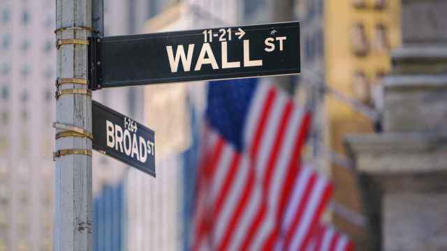 Cartel de Wall Street delante de unas banderas de EEUU.