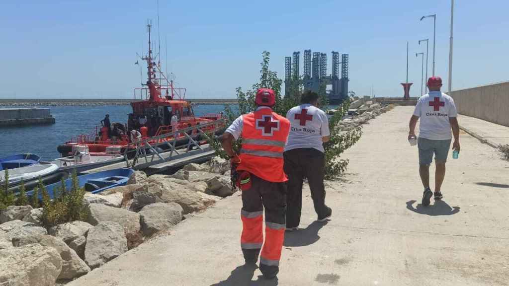 Miembros de Cruz Roja se dirigen hacia la embarcación que ha rescatado a los inmigrantes en Calpe, tras llegar al puerto de Alicante.