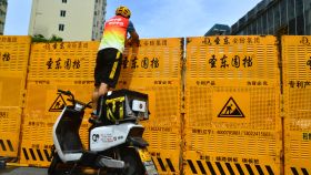 Un mensajero hace una entrega sobre una barricada en Sanya, China.