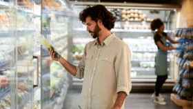Imagen de archivo de un hombre que comprueba la etiqueta de un producto en el supermercado.