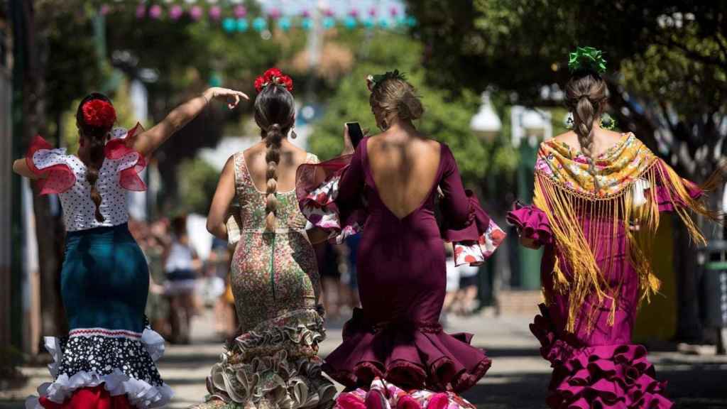 Tres personas vestidas de flamenca en la Feria de Málaga.