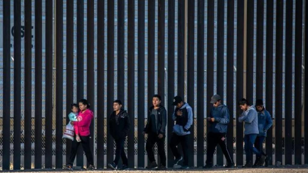 Migrantes junto al muro en la frontera con Texas.