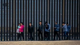 Migrantes junto al muro en la frontera con Texas.