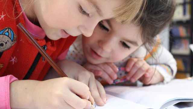 Dos niños  dibujando en un cuaderno.
