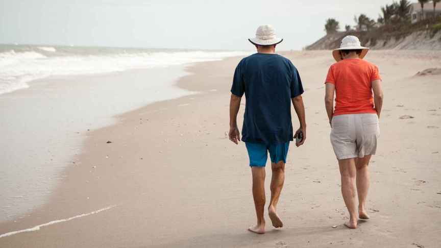 Una pareja pasea por la playa en un viaje del Club de los 60