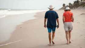 Una pareja pasea por la playa en un viaje del Club de los 60
