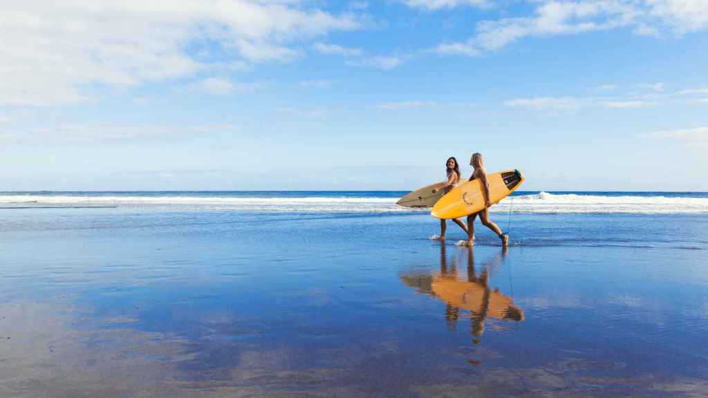 Dos chicas terminan su práctica de surf en la Playa del Socorro.