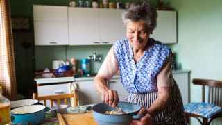 Imagen de archivo de una mujer mayor cocinando.