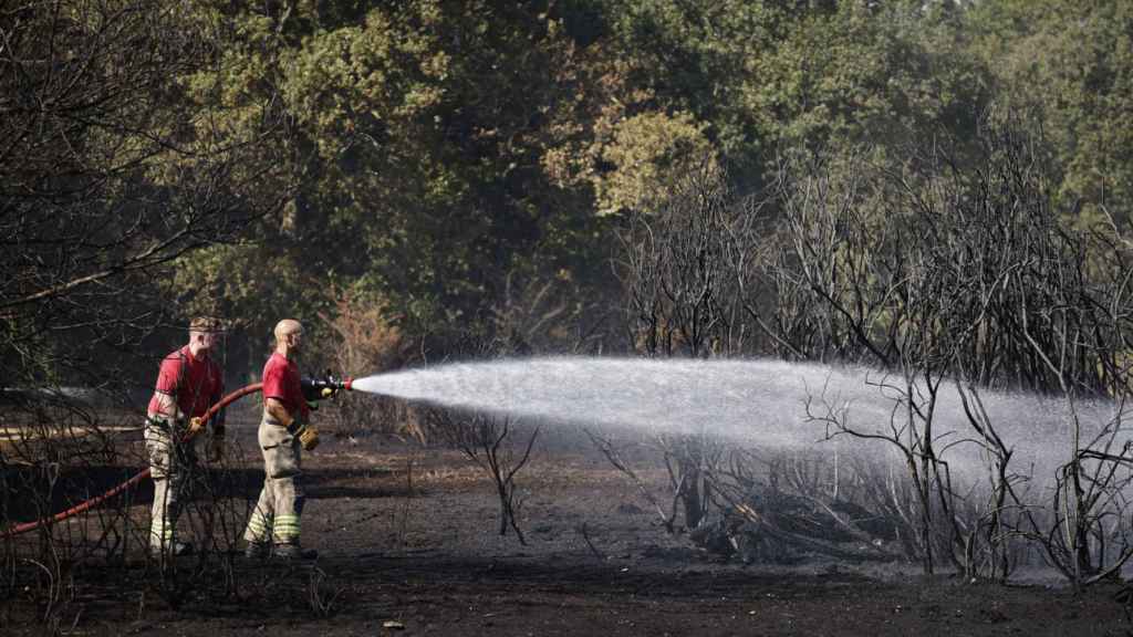 Unos bomberos refrescan un terreno después de que el Gobierno declarase el estado de sequía.