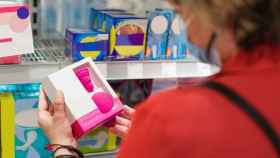 Imagen de archivo de una mujer en el lineal de higiene menstrual en un supermercado.