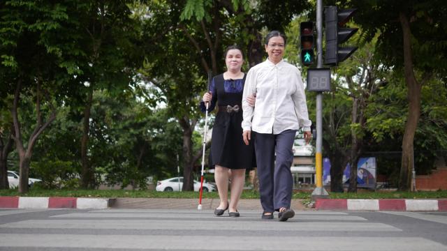 Una persona ciega es asistida para cruzar la calle