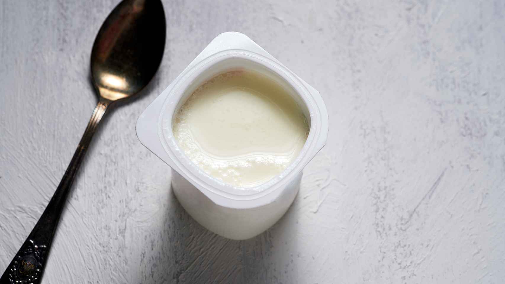 Un yogur natural con una cuchara.