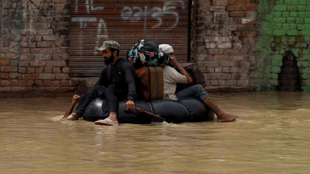 Unos hombres evacuados de sus casas en una balsa hinchable en Charsadda, Pakistán.