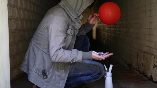 Un hombre con cartuchos de óxido nitroso, un sifón y un globo.